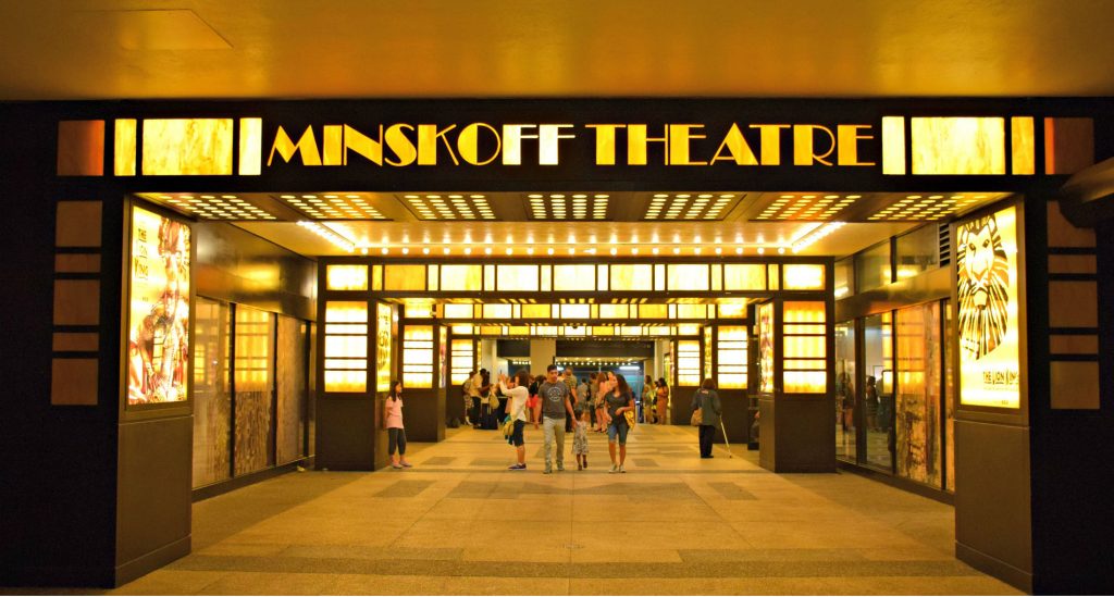 minskoff theatre entrance, sign in yellow lights with people exiting