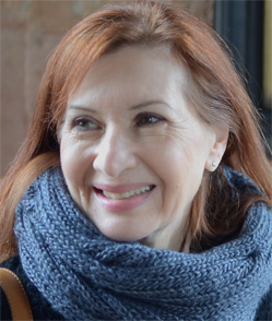 Woman with red hair in a gray scarf smiling at something off-camera