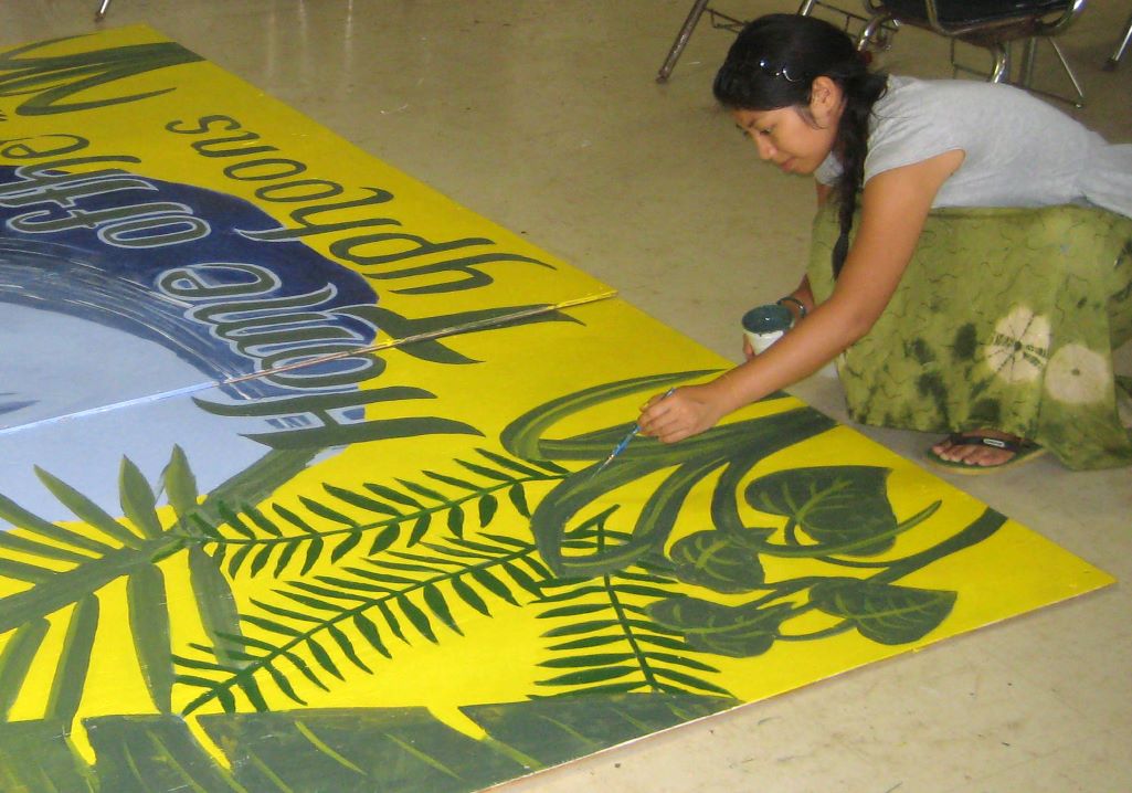  Woman wearing a white shirt painting a yellow mural on the ground