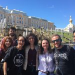 group of people smiling for a picture in front of white buildings in Russia