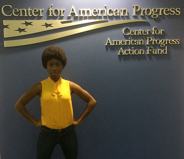 a women in yellow blouse standing proudly in front of the Center for American Progress sign