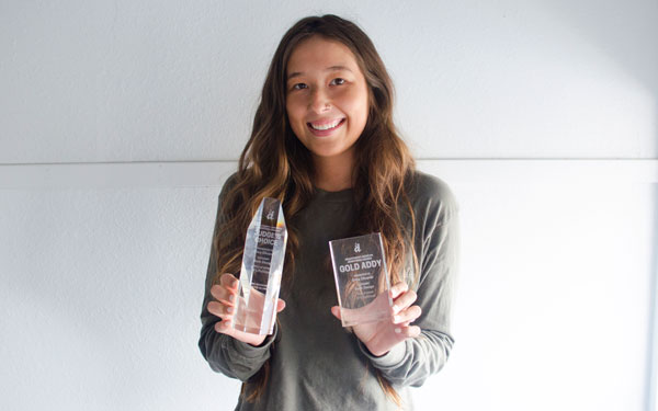 image of woman with brown hair and brown eyes holding her two awards