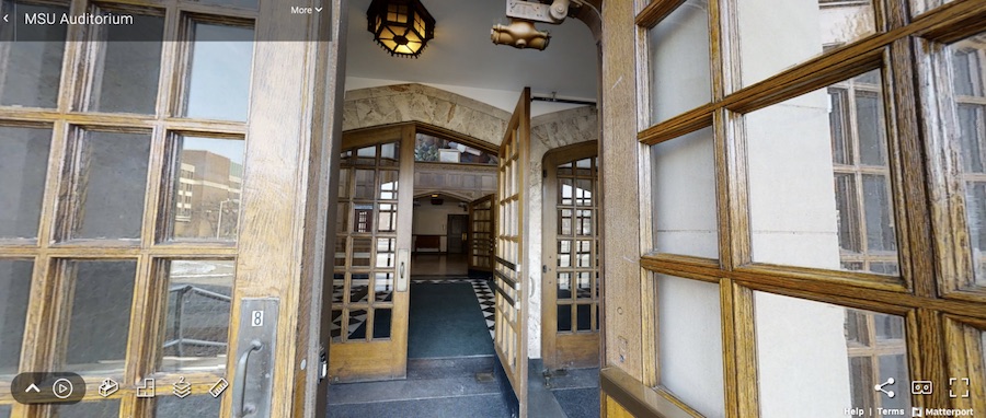 Image of the entryway of a theatre. The doors are wooden and are installed in archways. The doors have glass panes.