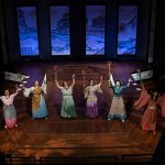 Ariel shot of a group of eight women wearing dresses on a stage