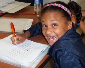 girl smiling while working with pencil in a notebook