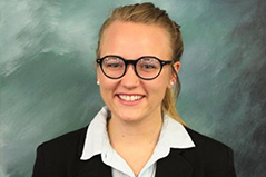 girl with hair up in a pony tail wearing glasses, a white shirt and a black blazer