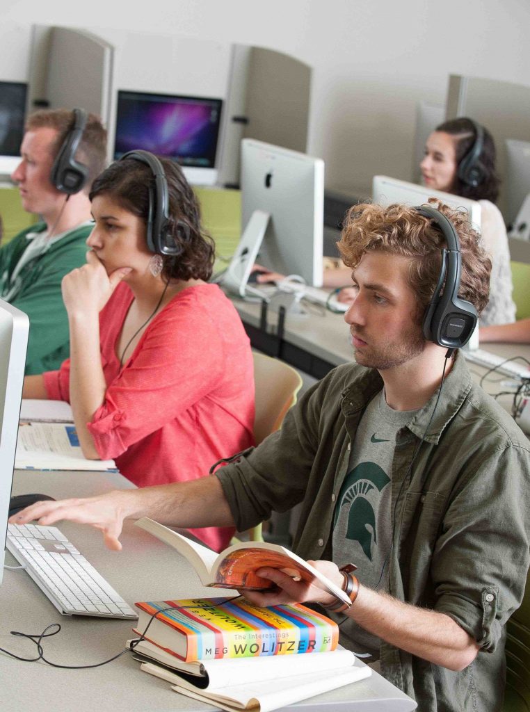 students working on laptops wearing headphones 