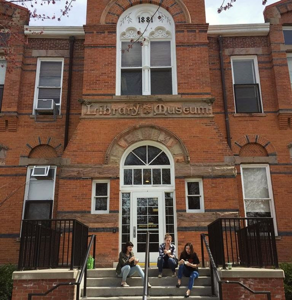 three students sitting in front of a brick building 