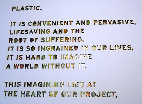 art piece with cut out letters discussing the harm of plastic on top of recycled materials