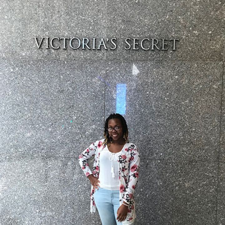 Woman with glasses standing in front of the Victoria's Secret logo