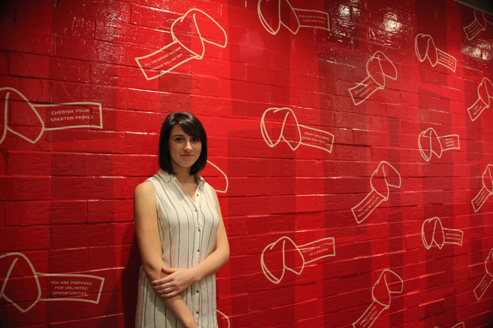 Chloe Jennings in front of her fortune cookie design mural