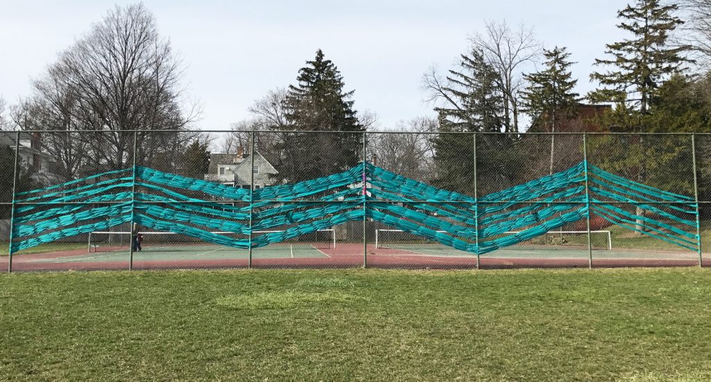 Photo of teal ribbon art installation on chain link fence 