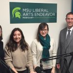 four people smiling in front of a poster that says "MSU liberal arts endeavor podcast"