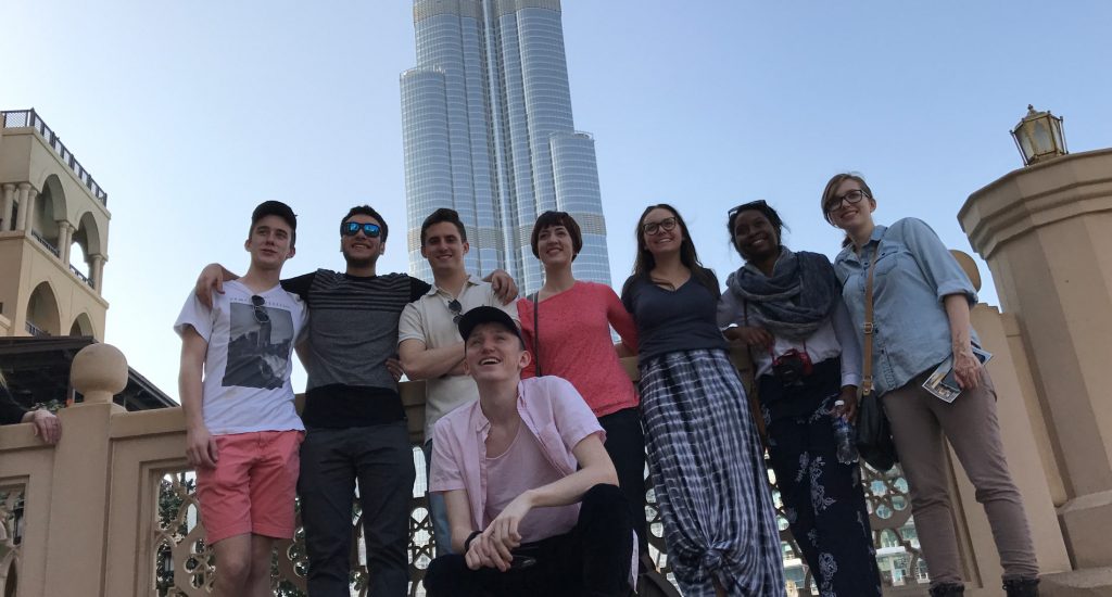 nine people standing together in front of the Dubai cityscape