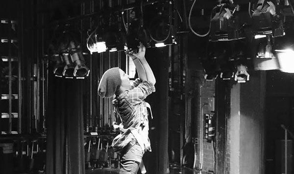 black and white photo of a man working on stage lights