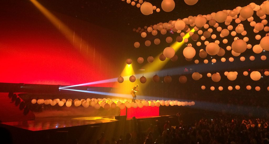 Red and orange lighting in large sphere lanterns over an audience and stage