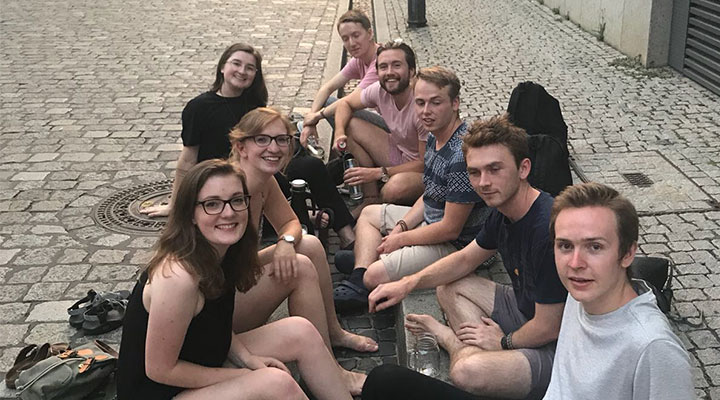 group of people sitting on a coblestone sidewalk