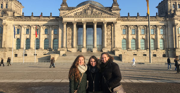 three woman posing in front of classical building with columns