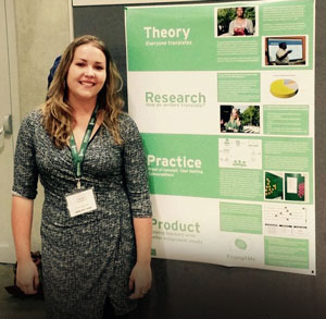 woman with blonde hair standing next to her poster presentation