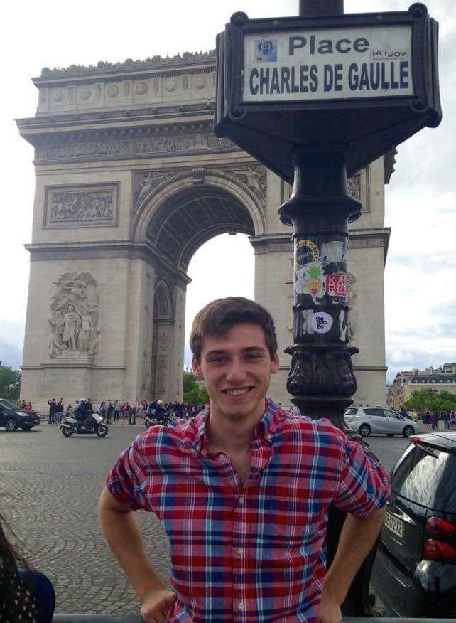a guy standing next to a sign in Paris