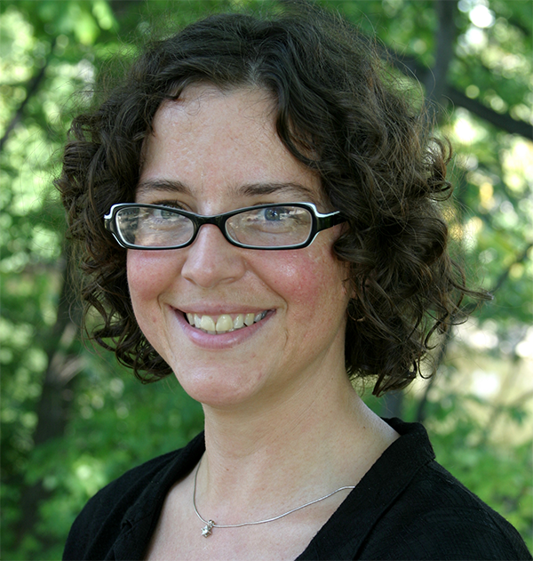 headshot of a woman with brown curly hair and glasses