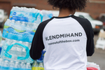 the back of a person wearing a shirt with "LendMIHand" on it and water bottles in the background