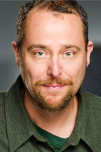 close up of man with short brown hair and goatee wearing a green polo