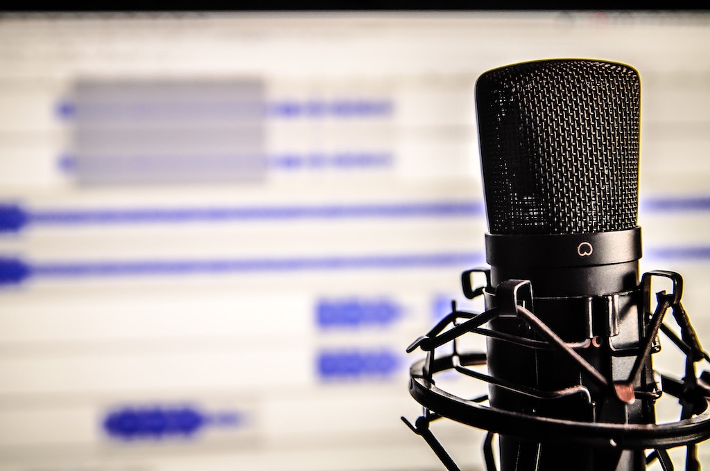 black microphone sitting in front of a blurred computer screen that has a white background and blue lines of different sizes on it  