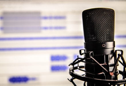 black microphone sitting in front of a blurred computer screen that has a white background and blue lines of different sizes on it