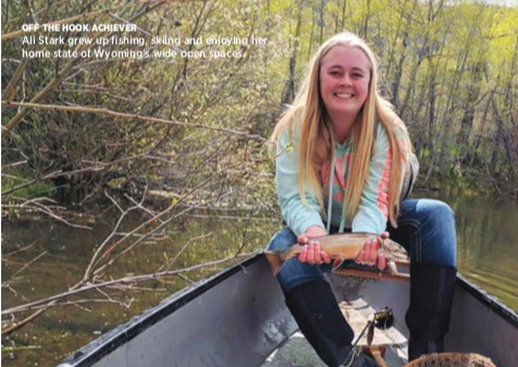 picture of a woman with straight, blonde hair sitting in a canoe and smiling, she is wearing a light blue sweater and jeans