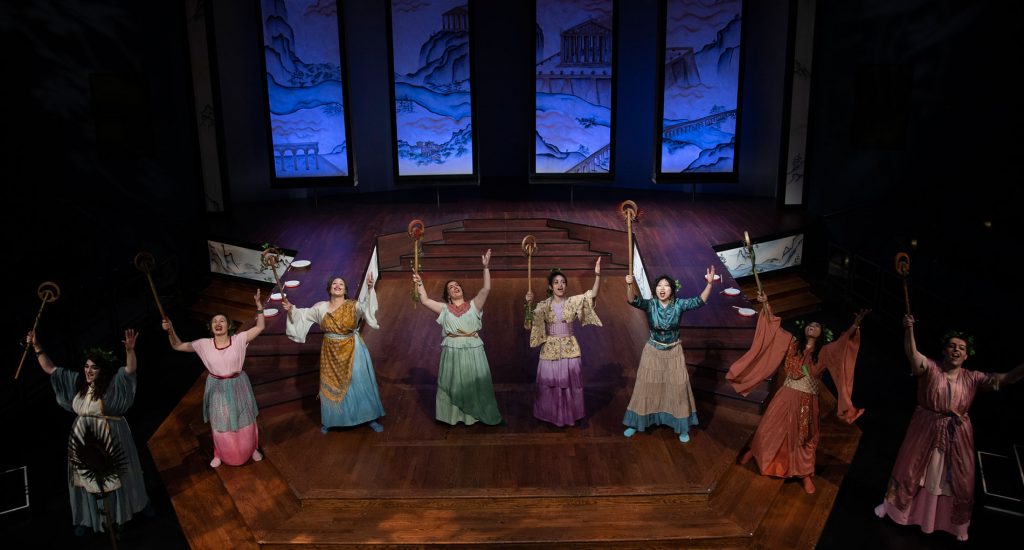 Ariel shot of a group of eight women wearing dresses on a stage 