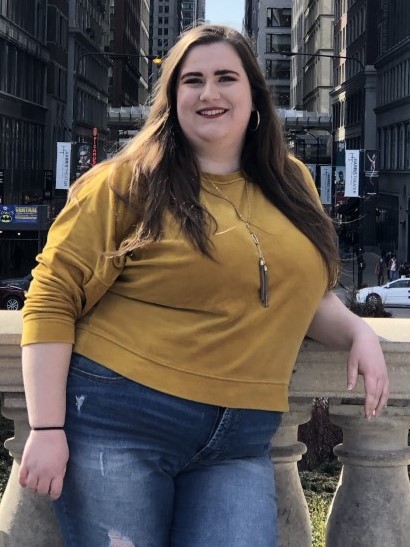 a girl with brown hair wearing a yellow shirt and jeans