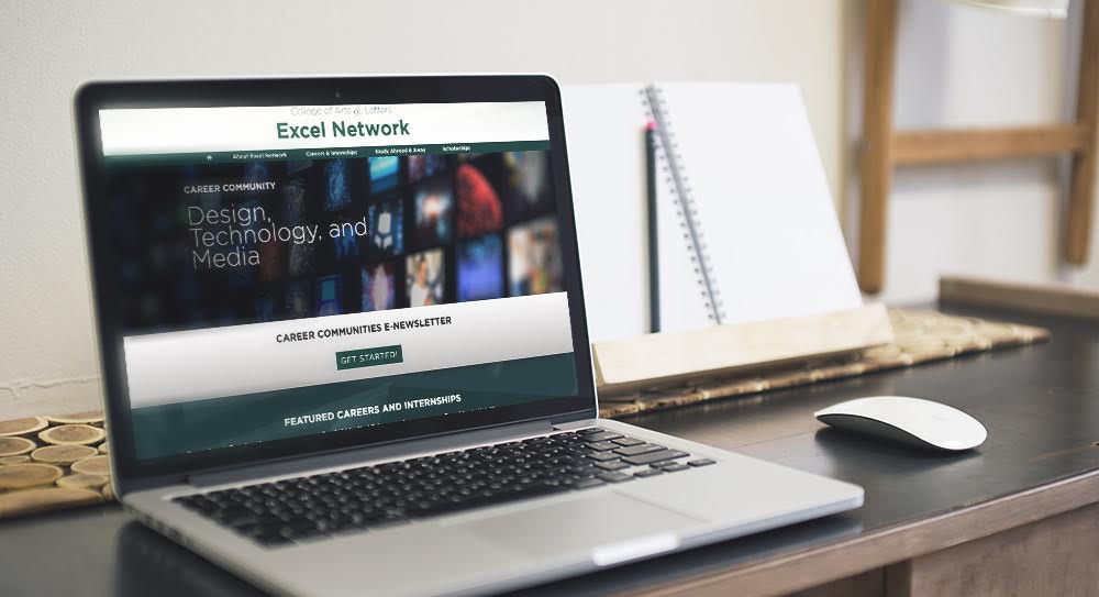 laptop on desk showing excel network website homepage