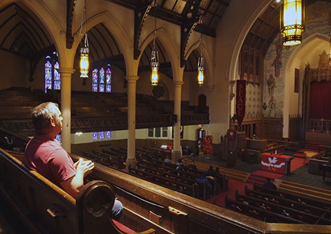 Man wearing red sitting in a church praying