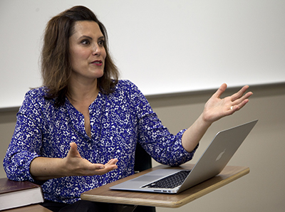 woman with brown hair sitting in front of laptop talking to class