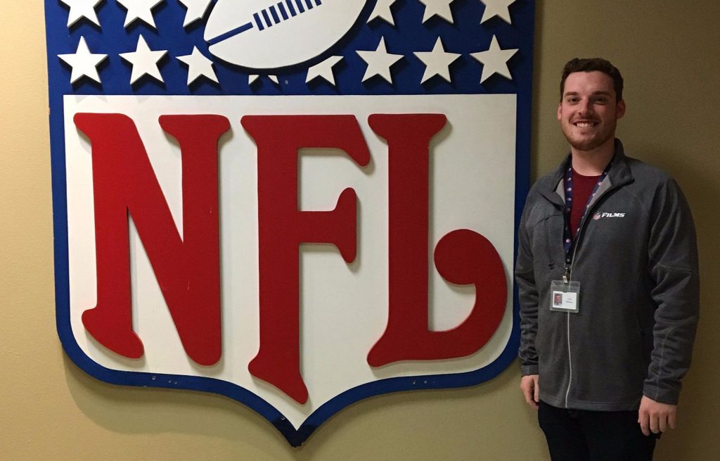 man standing next to NFL sign
