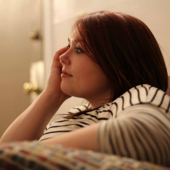 woman wearing a stripped shirt resting her head on her hand