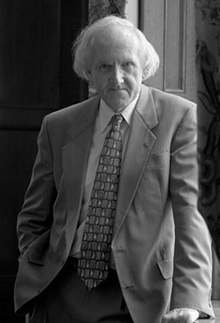 Man with long white hair in light colored suit