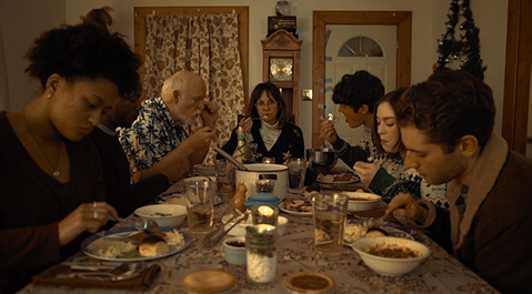 seven people sitting at a table eating food