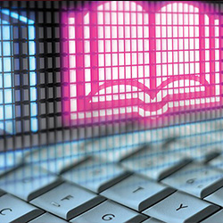a computer keyboard with a pink neon sign of a book