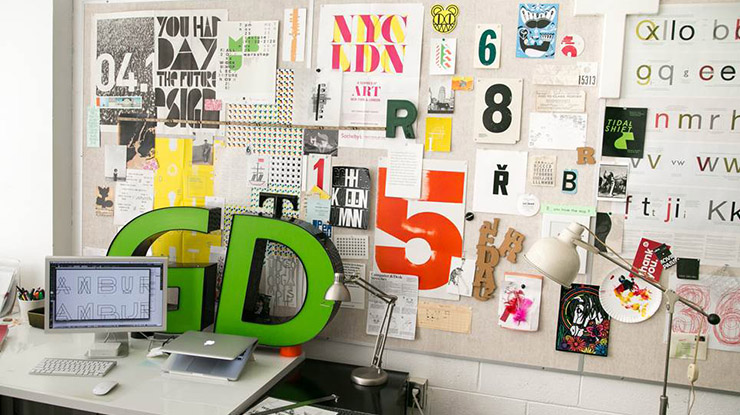 cluttered desk up against a wall covered in graphics and typography