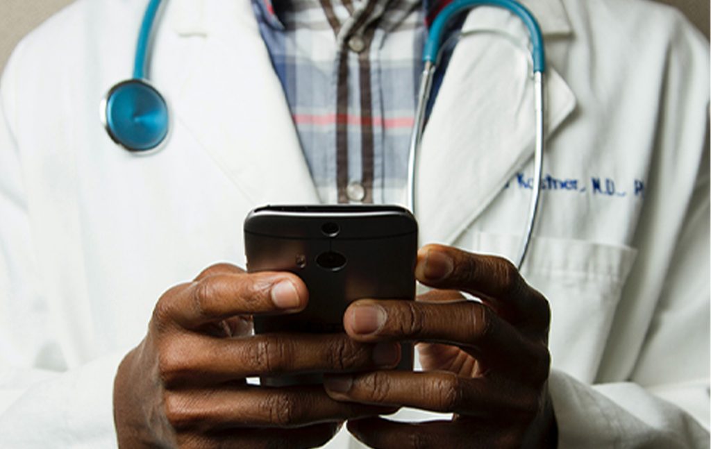 a person wearing a white doctor coat with a stethoscope around their neck and holding a phone 