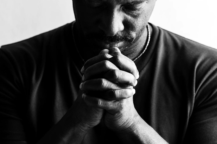 black and white photo of a mans hands clasped in prayer