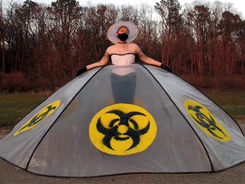 Woman in a large gown with biohazard symbols along the bottom