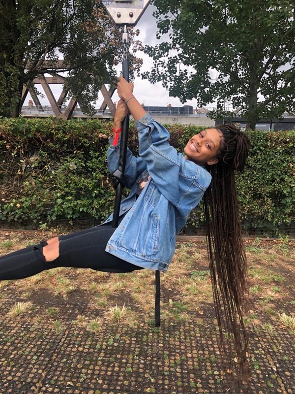 image of a girl with long braided hair swinging wearing a jean jacket and black jeans