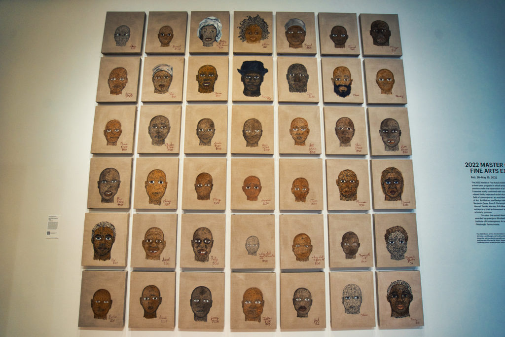 A series of paintings depicting faces hangs on the wall.
