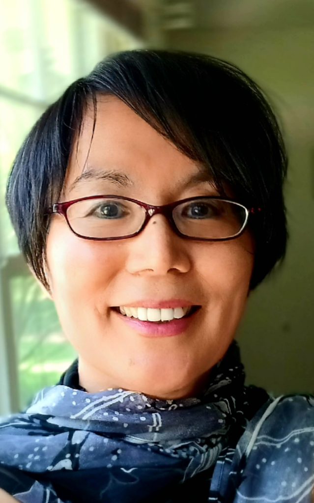 Portrait of a smiling woman with short, dark hair and glasses.