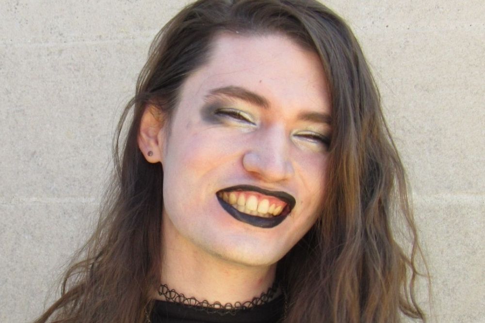 Portrait of a smiling young woman with black lipstick.