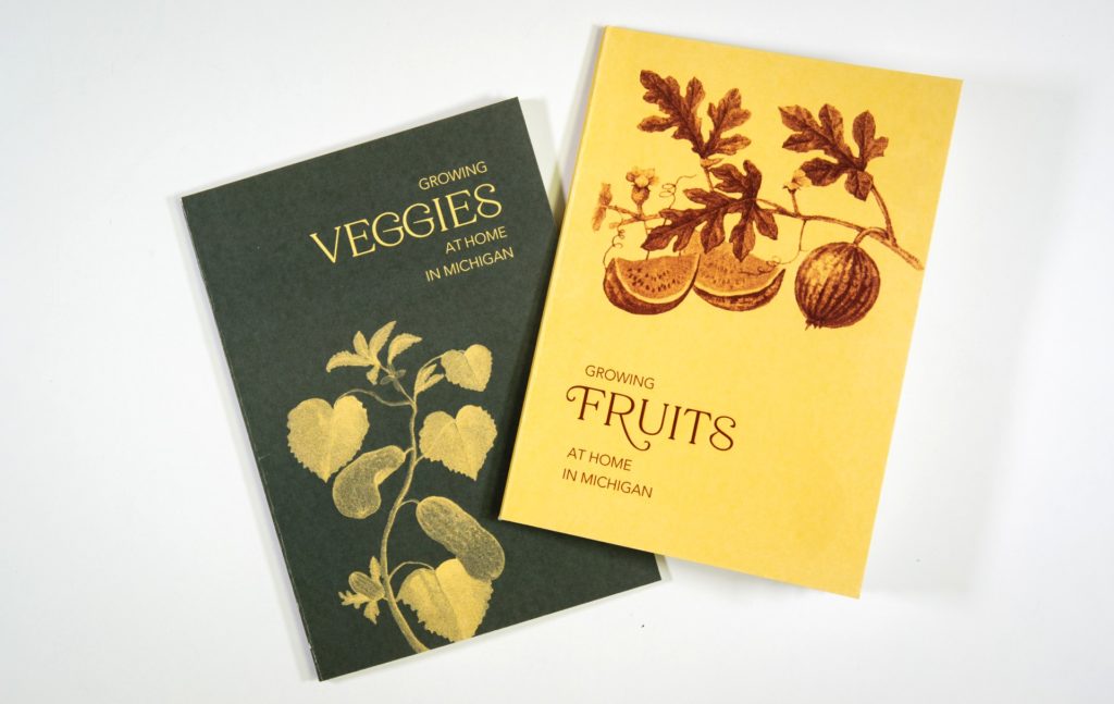 Two pamphlets, one dark green with a yellow cucumber plant illustration and the words "Growing Veggies at Home in Michigan" on the left and a second yellow one with a brown watermelon plant illustration and the words "Growing Fruits at Home in Michigan" on the right, lay overlapping each other. 