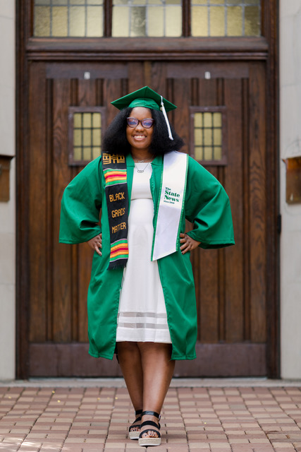 Photo of a woman (SaMya Overall) who is standing and is wearing a green cap and gown.